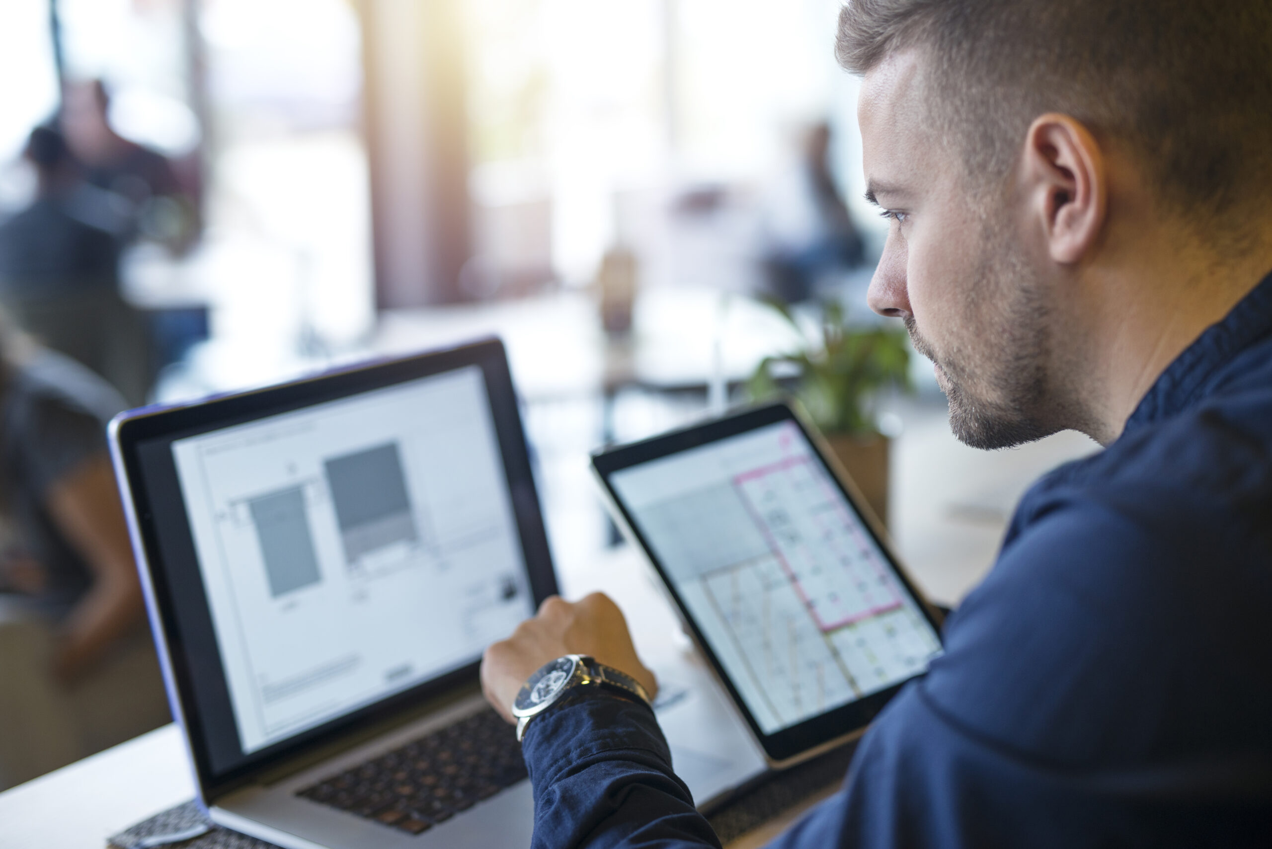 How electrical project management software transforms electrical operations, shown by an electrical professional reviewing project plans on a laptop and tablet.