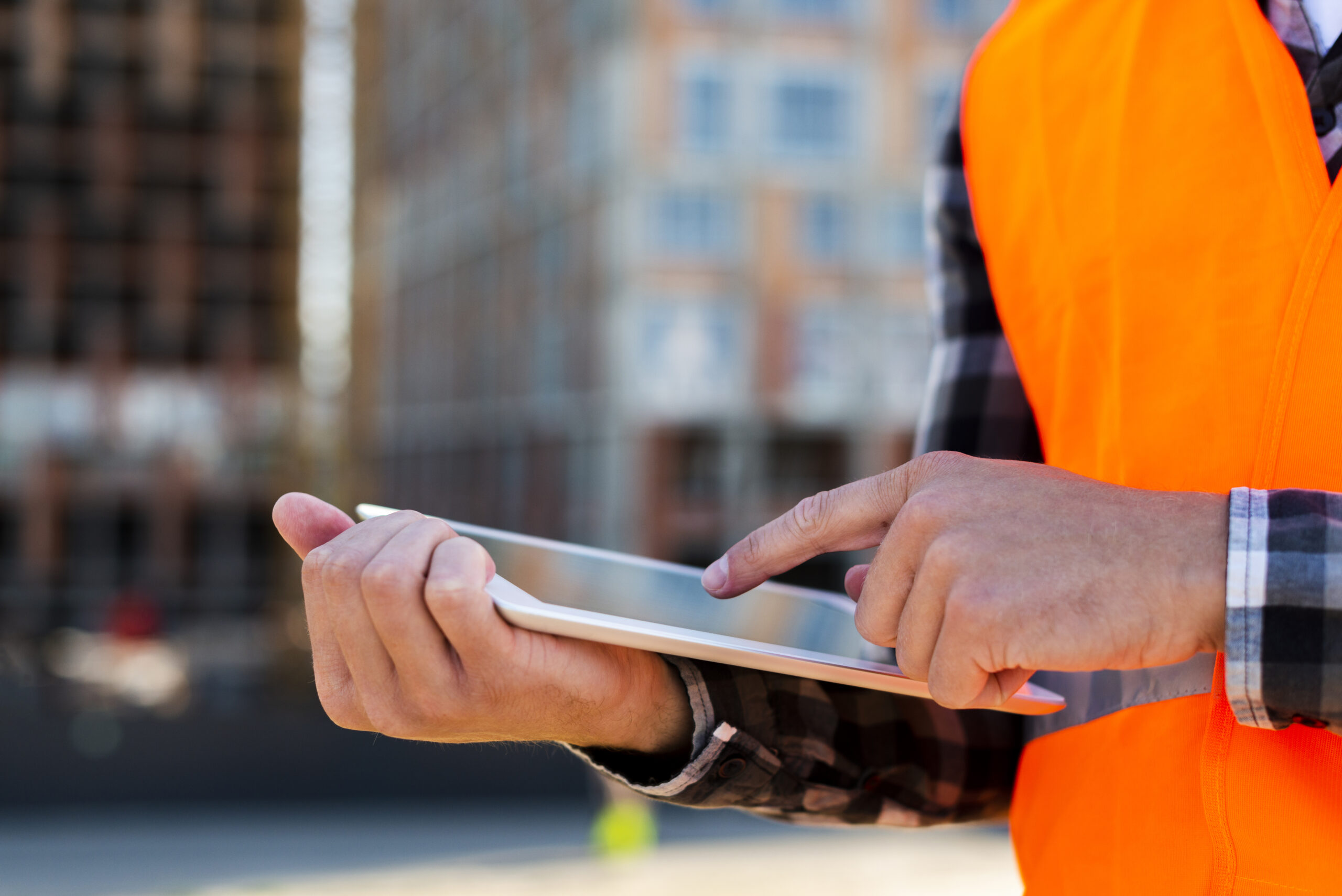 Workflow automation with electrical project management software shown by a site supervisor using a tablet to manage tasks and updates on a construction site.