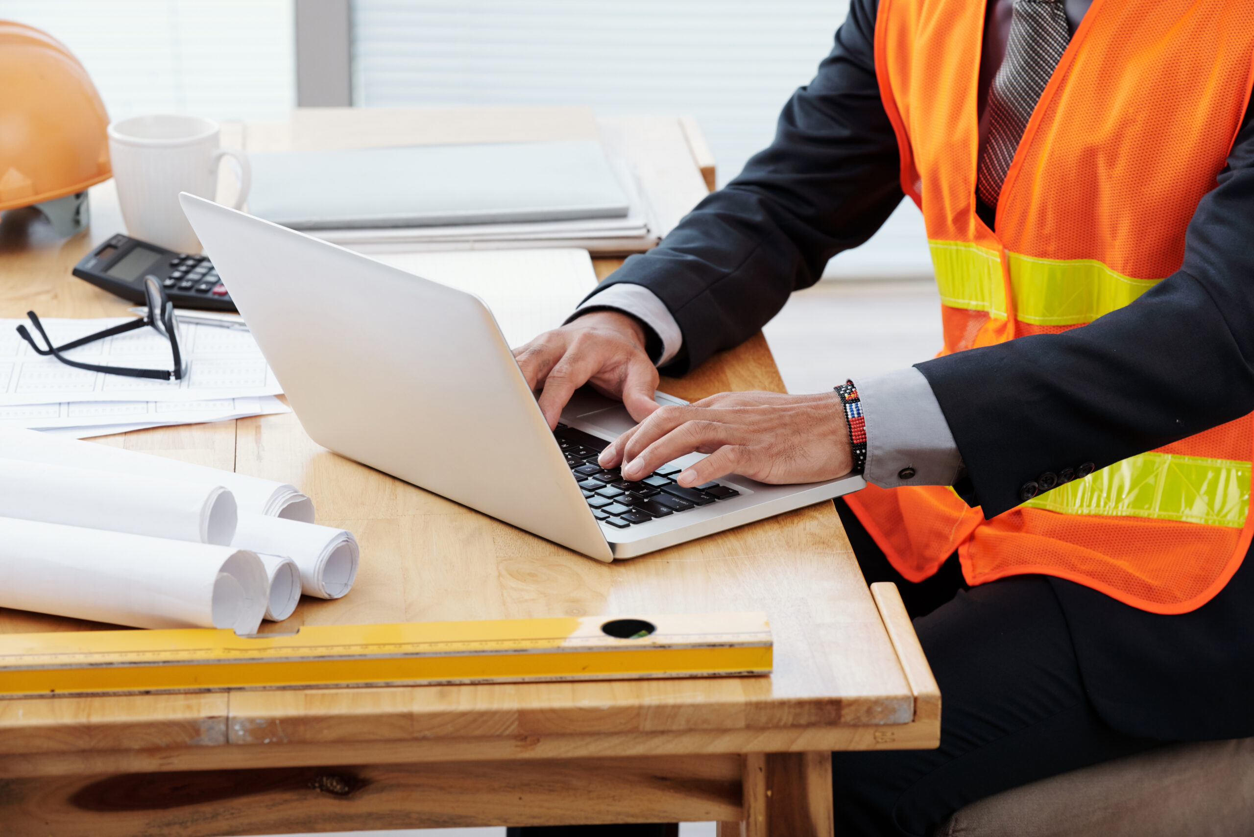 Key compliance benefits of mechanical project management software shown by a mechanical professional using a laptop to manage drawings, documentation, and compliance records at a desk.