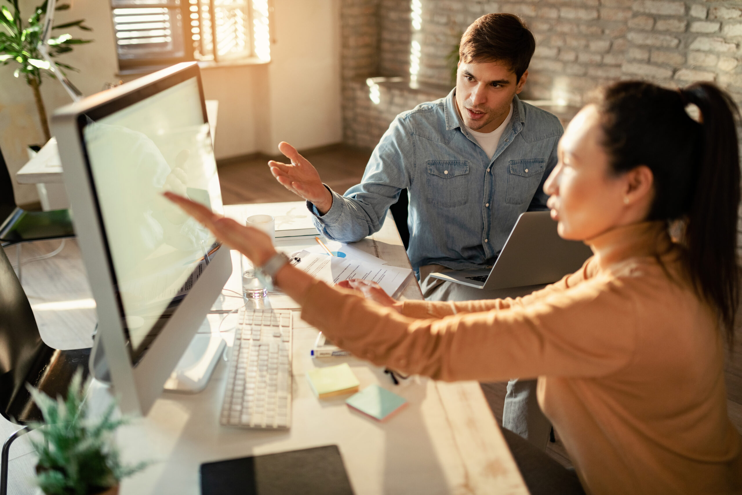 How to train staff on electrical project management software, shown by team members reviewing workflows and guidance together on a desktop computer.