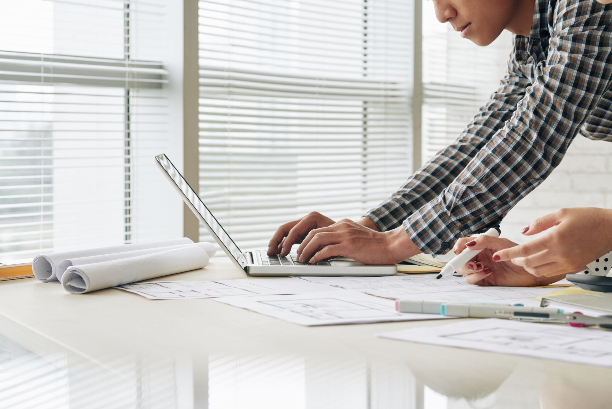 Two professionals review data charts on a tablet, showcasing the top features to look for in electrical project management software like real-time analytics.