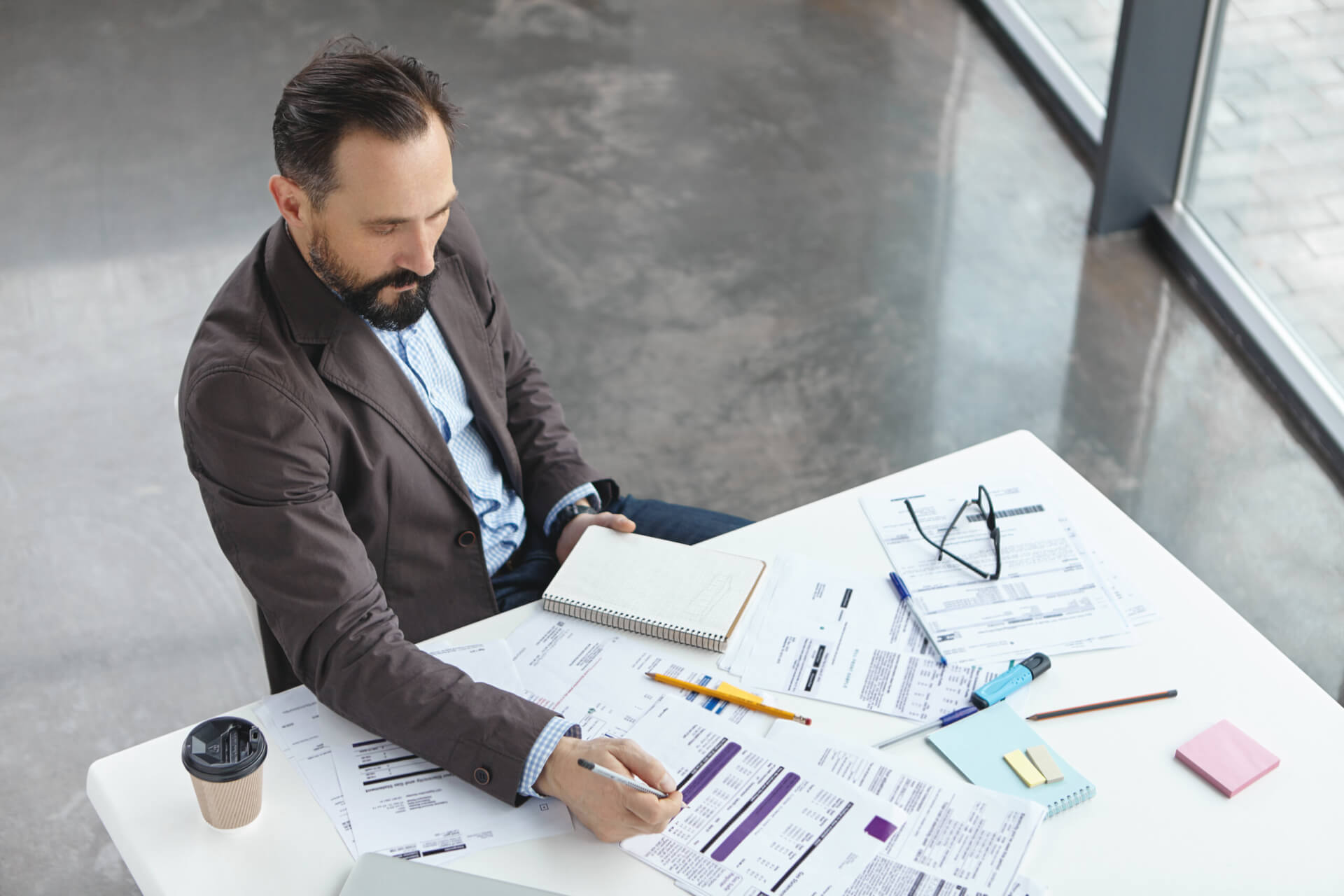 A project manager reviewing spreadsheets and documents at a desk, illustrating the common mechanical mistakes that project management software helps to solve.
